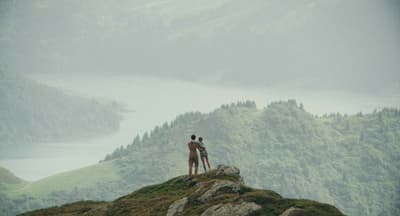 Image du film Bergers, un couple s'enlace en face de l'horizon des montagnes et d'un lac
