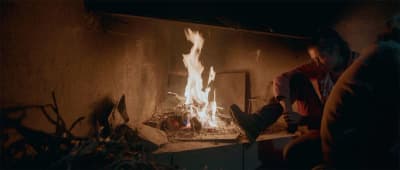 Un femme est assise devant un feu